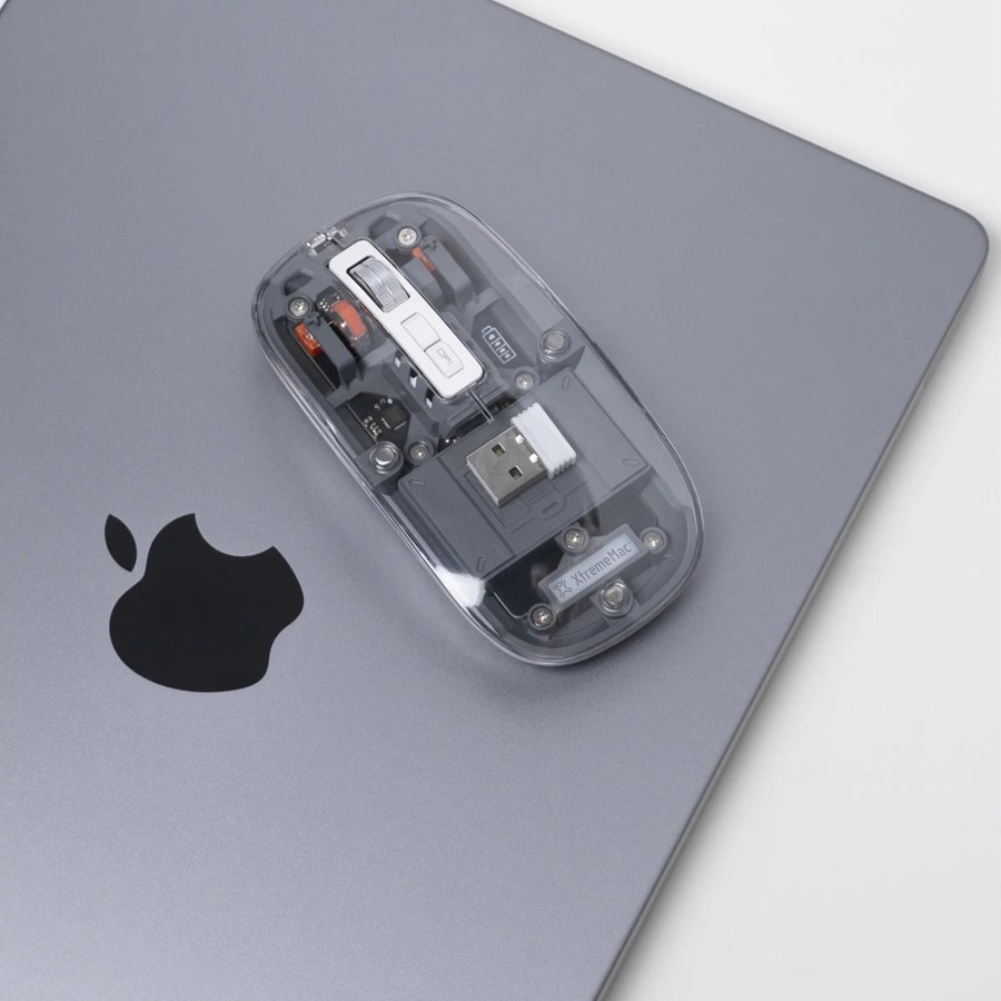 Mouse trasparente su un laptop, che mostra i componenti interni e il logo Apple.