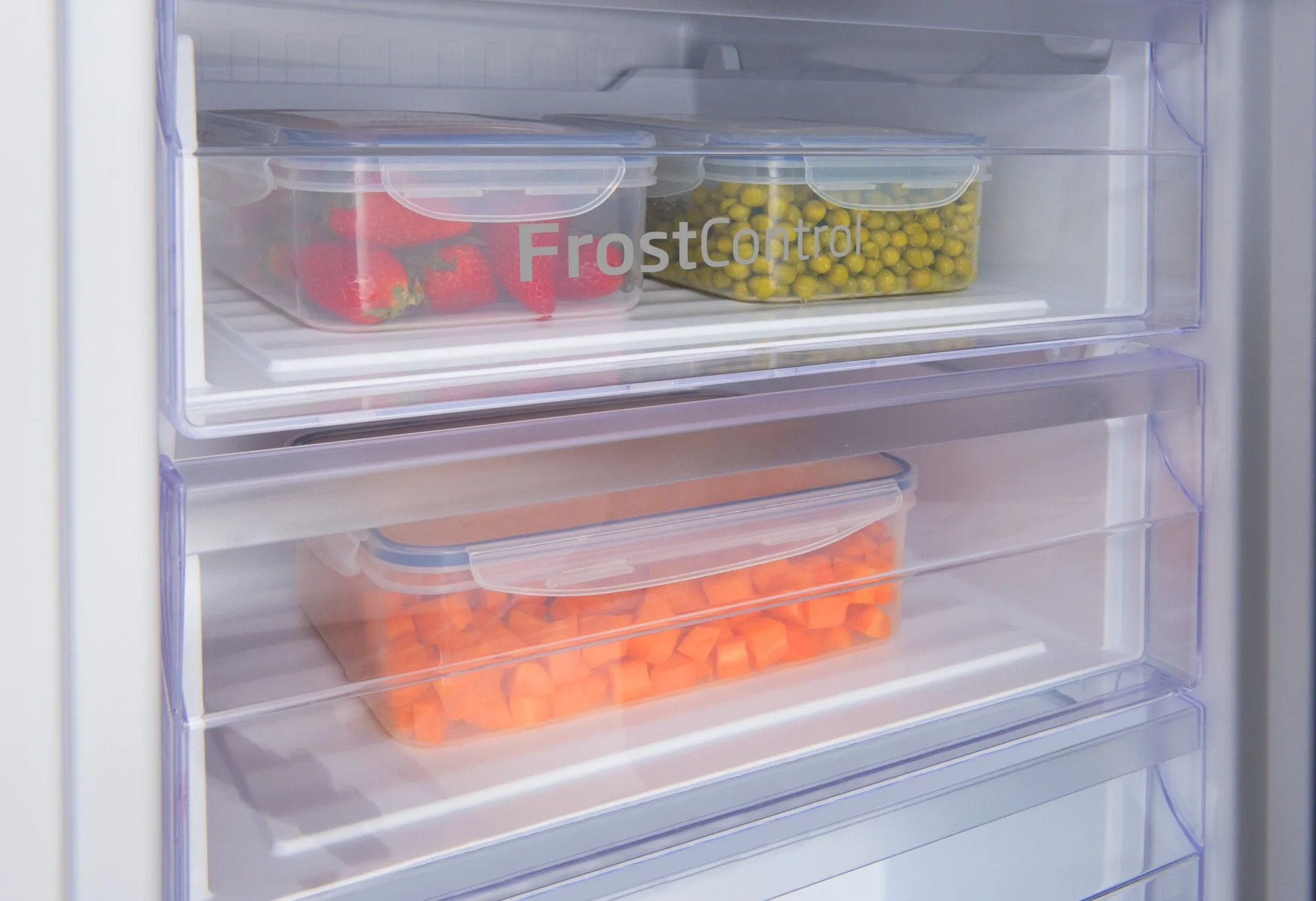 Zbliżenie wnętrza lodówki z przezroczystymi pojemnikami z jedzeniem.