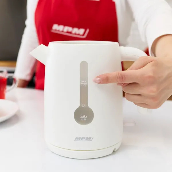 Ręka kobiety wskazuje wskaźnik poziomu wody białego czajnika elektrycznego.