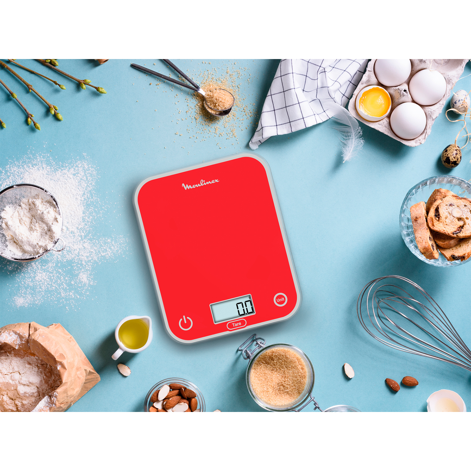 Bilancia da cucina Moulinex rossa con alimenti come uova e farina.