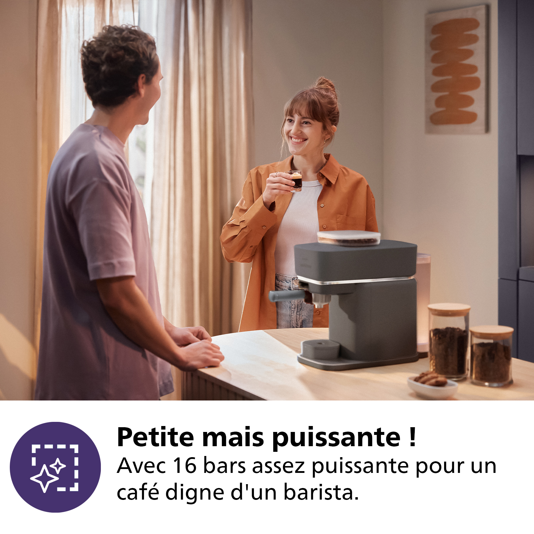 Un homme et une femme sourient, une machine à café sur un comptoir.