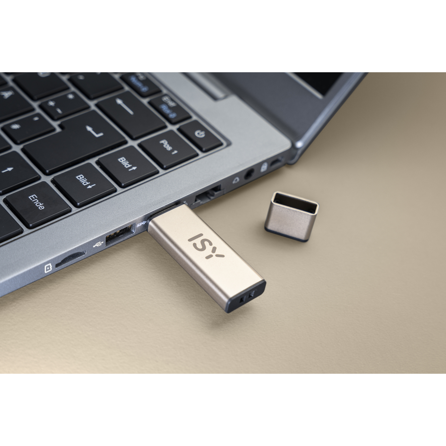 Une clé USB dorée branchée sur un ordinateur portable. Un capuchon assorti est également visible.