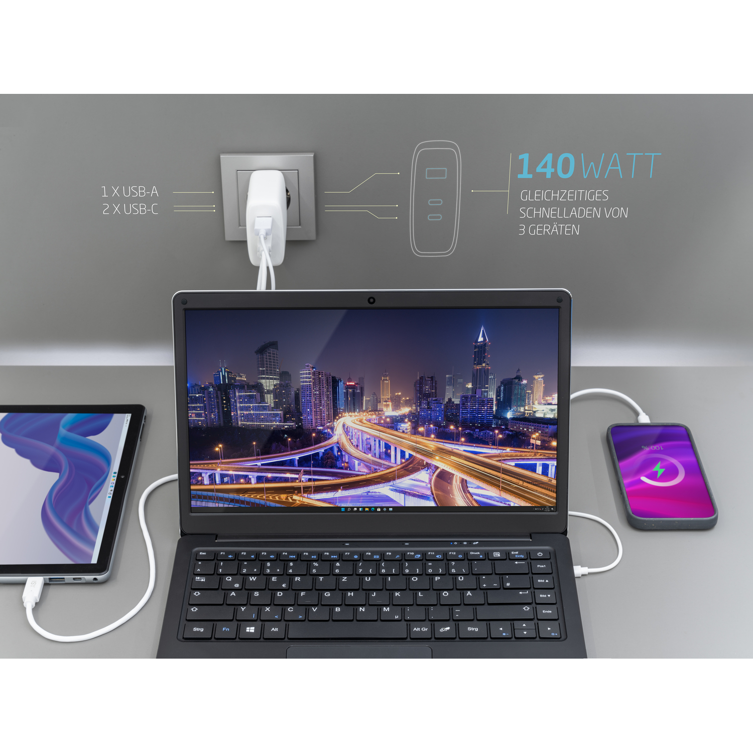 Een laptop, tablet en telefoon zijn aangesloten op een wandlader die in een stopcontact zit.