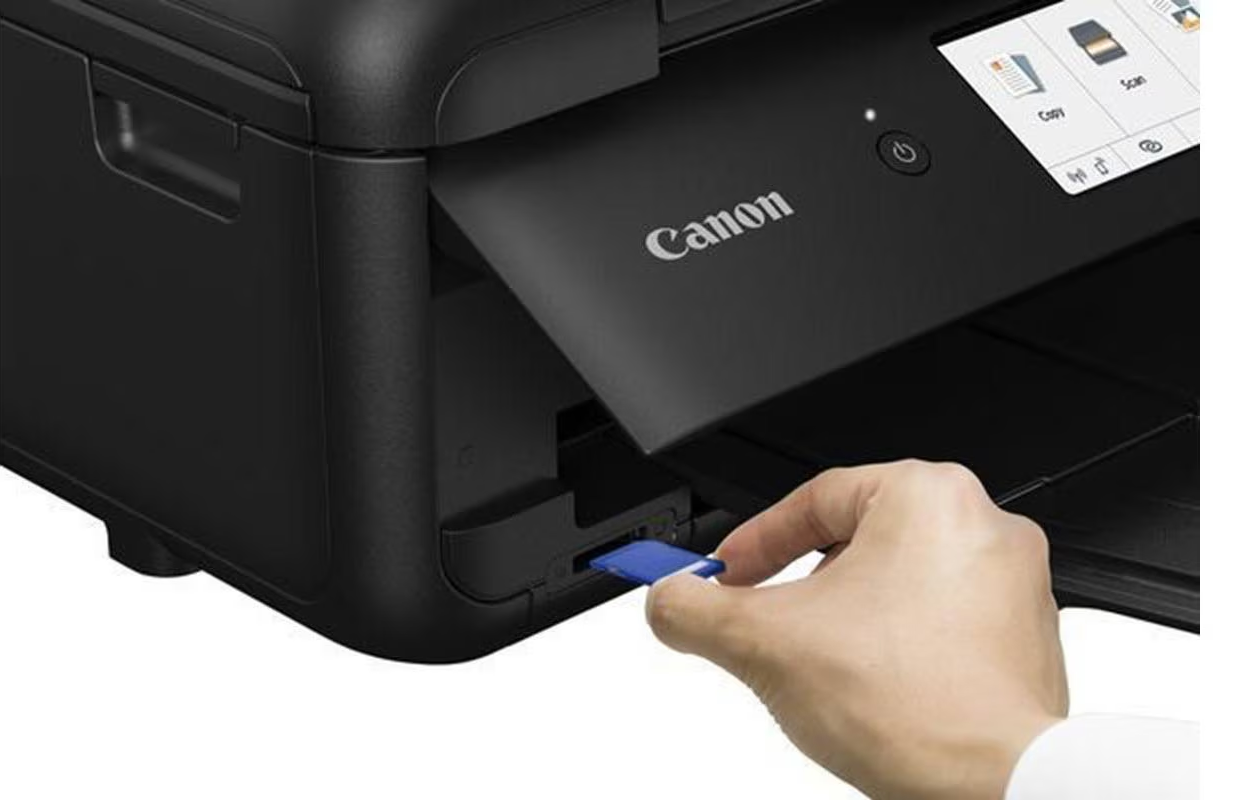 Hand, die eine blaue SD-Karte in einen schwarzen Canon-Drucker einführt, Nahaufnahme.