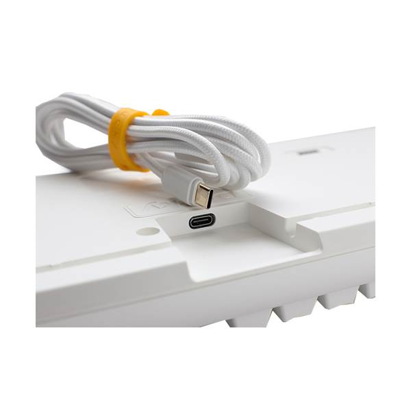 Primer plano de la parte trasera de un teclado blanco, cable con banda amarilla y puerto USB.