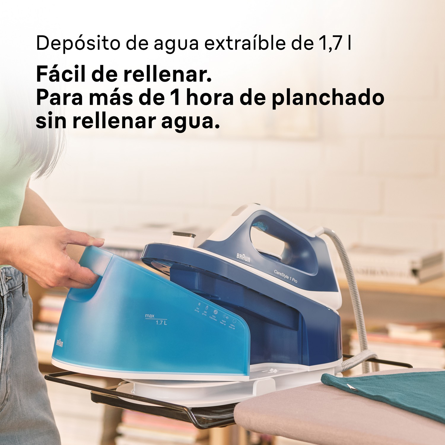 Mano de una persona llenando el depósito de agua de una plancha de vapor Braun azul y blanca.