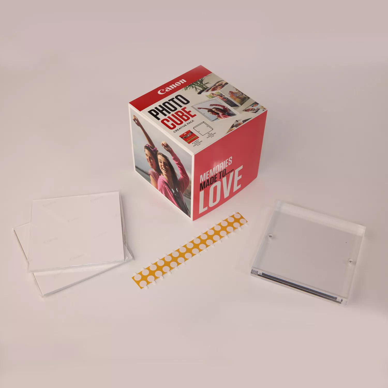 Canon Photo Cube Box mit Inhalt. Enthält Bilder, Klebeband und einen transparenten Rahmen.
