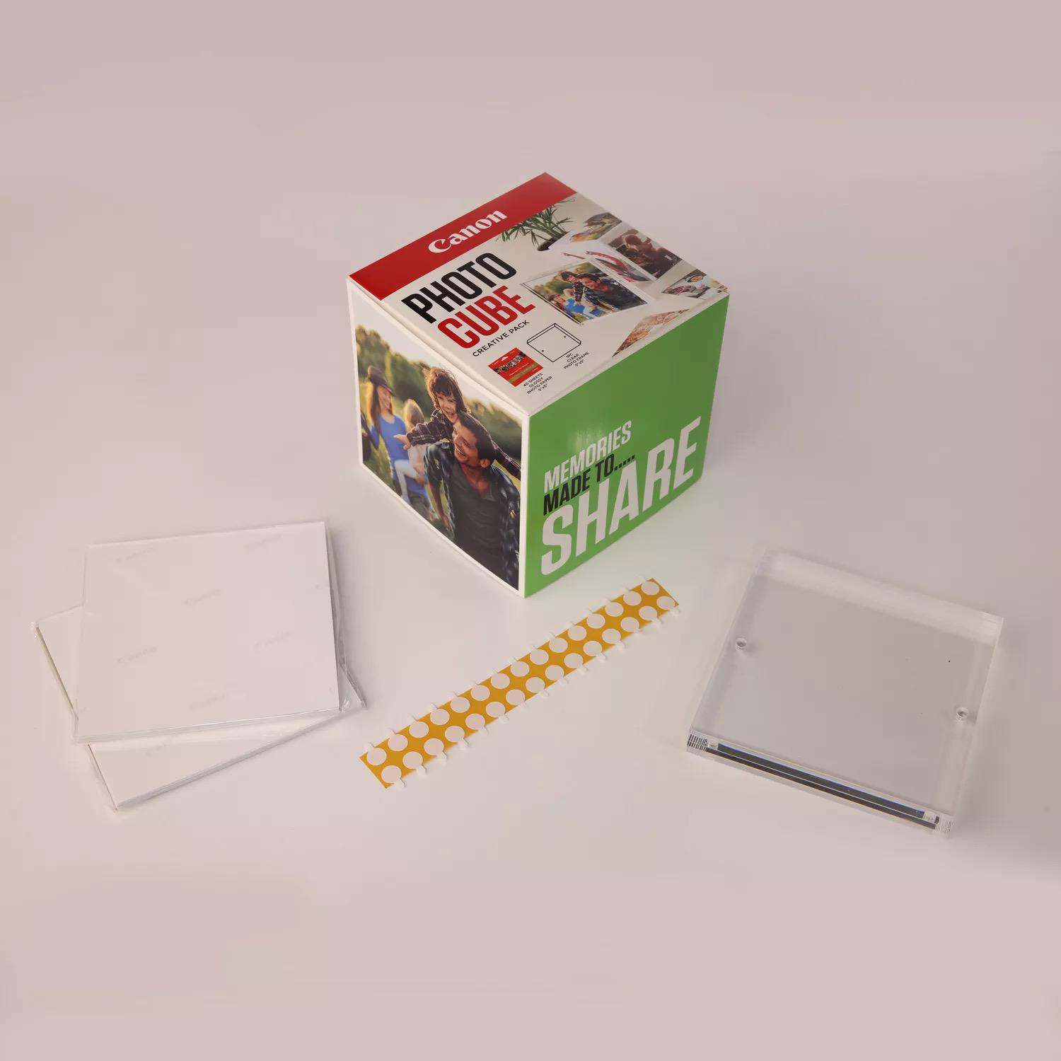 Eine Canon Photo Cube-Box mit Fotos, Aufklebern und transparenten Vitrinen.