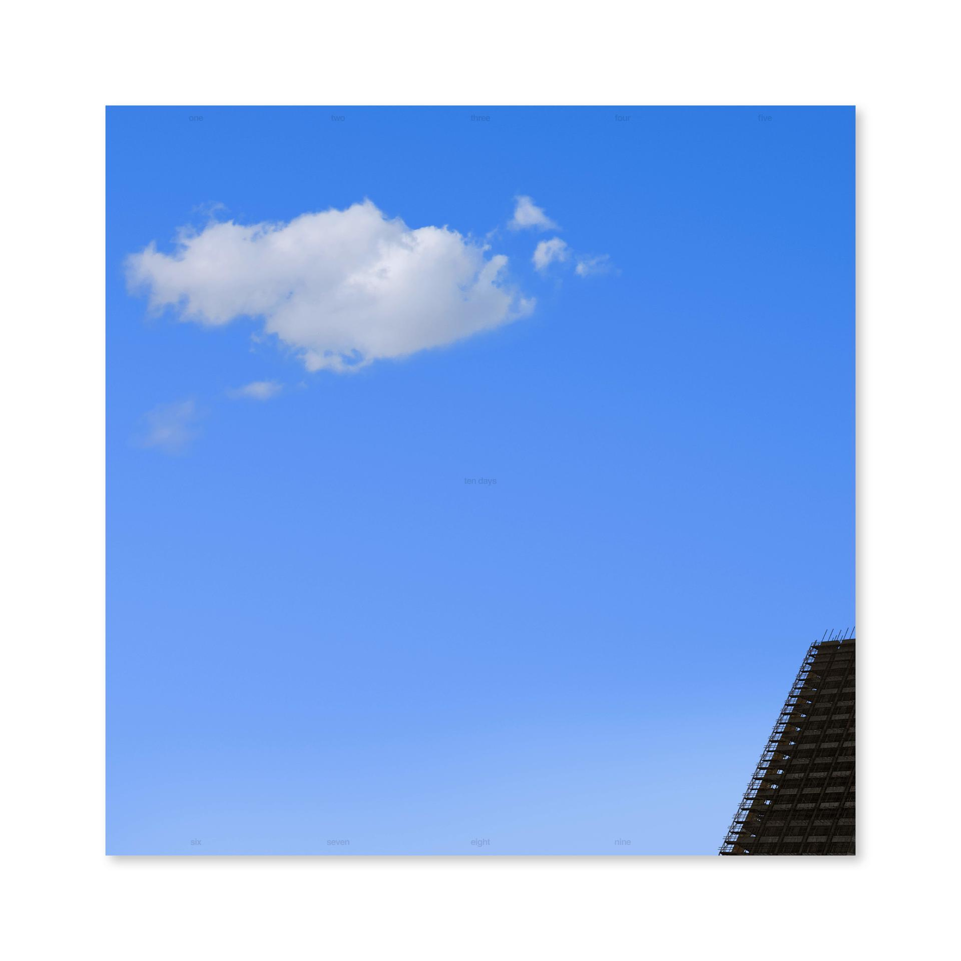 Ein quadratisches Bild eines blauen Himmels mit einer Wolke und einem Gebäude in der Ecke.