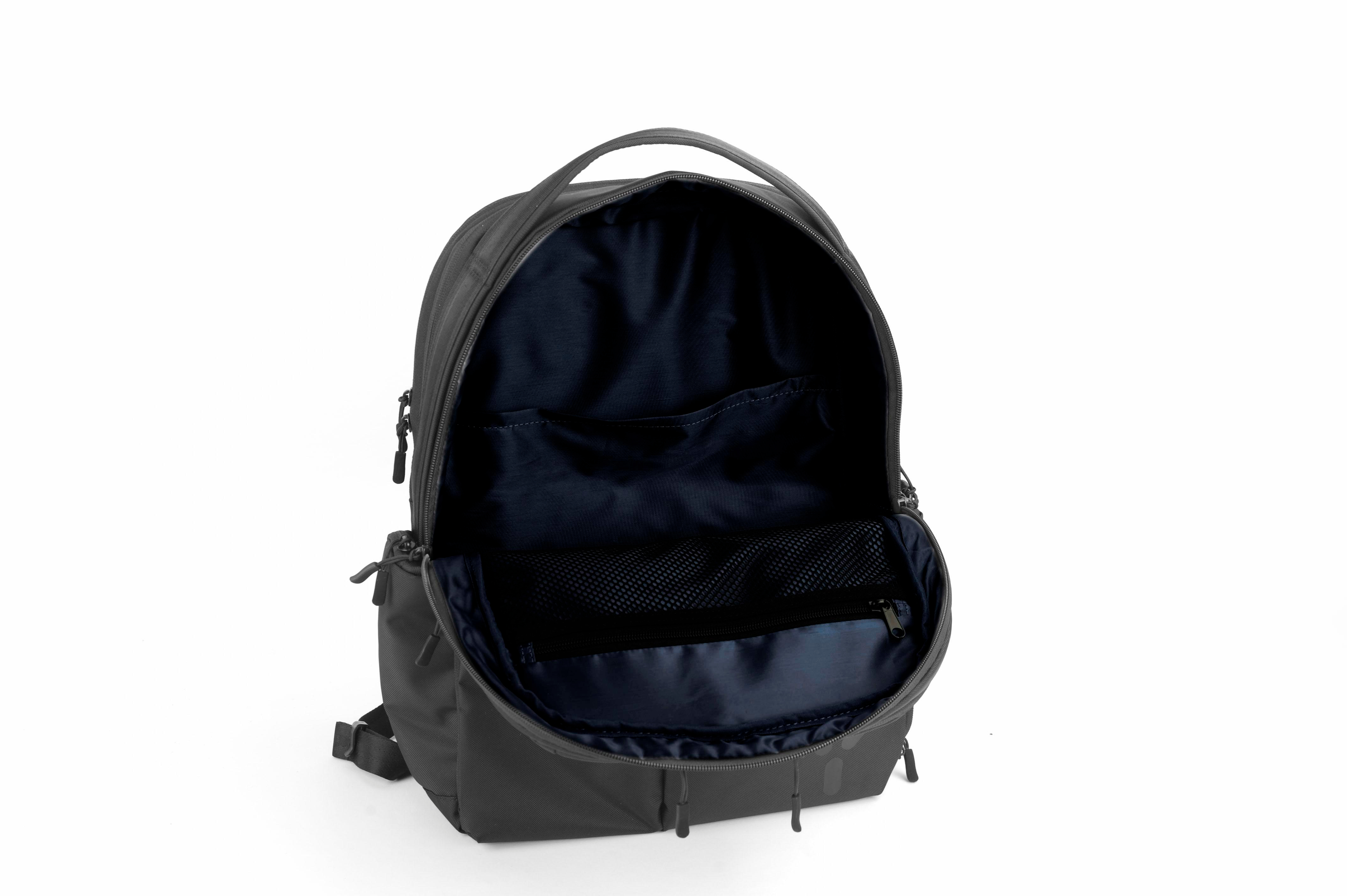 Offener grauer Rucksack mit dunkelblauem Innenraum. Weißer Hintergrund.