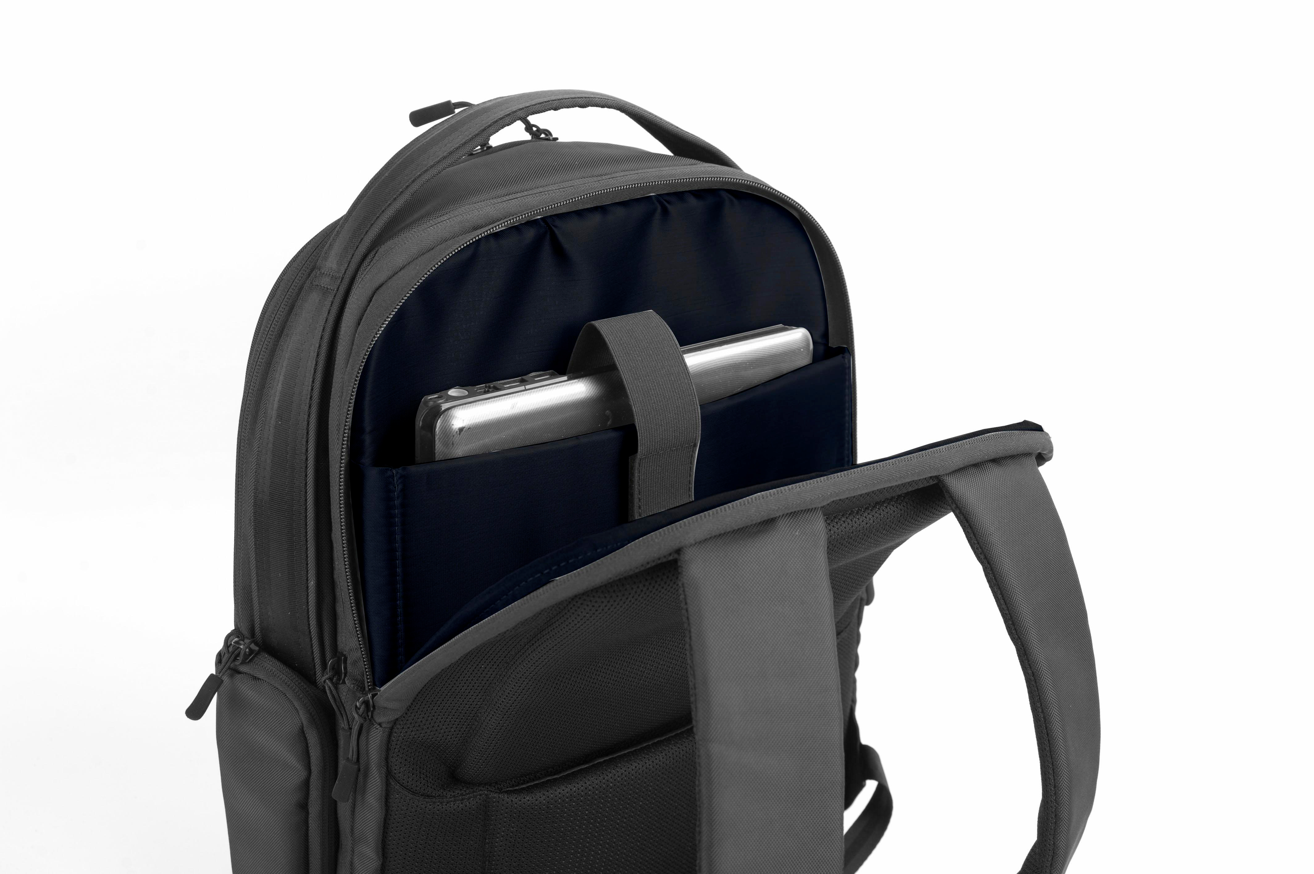 Ein grauer Rucksack mit offener Fronttasche, die ein Tablet und ein dunkelblaues Innere zeigt.