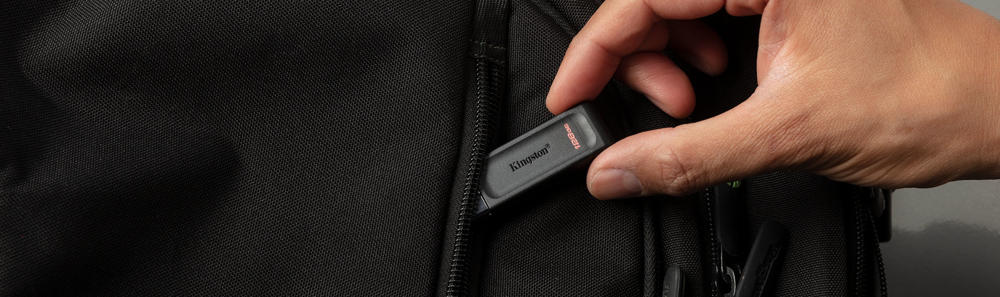Ein schwarzer USB-Stick, der in eine schwarze Tasche gesteckt wird.