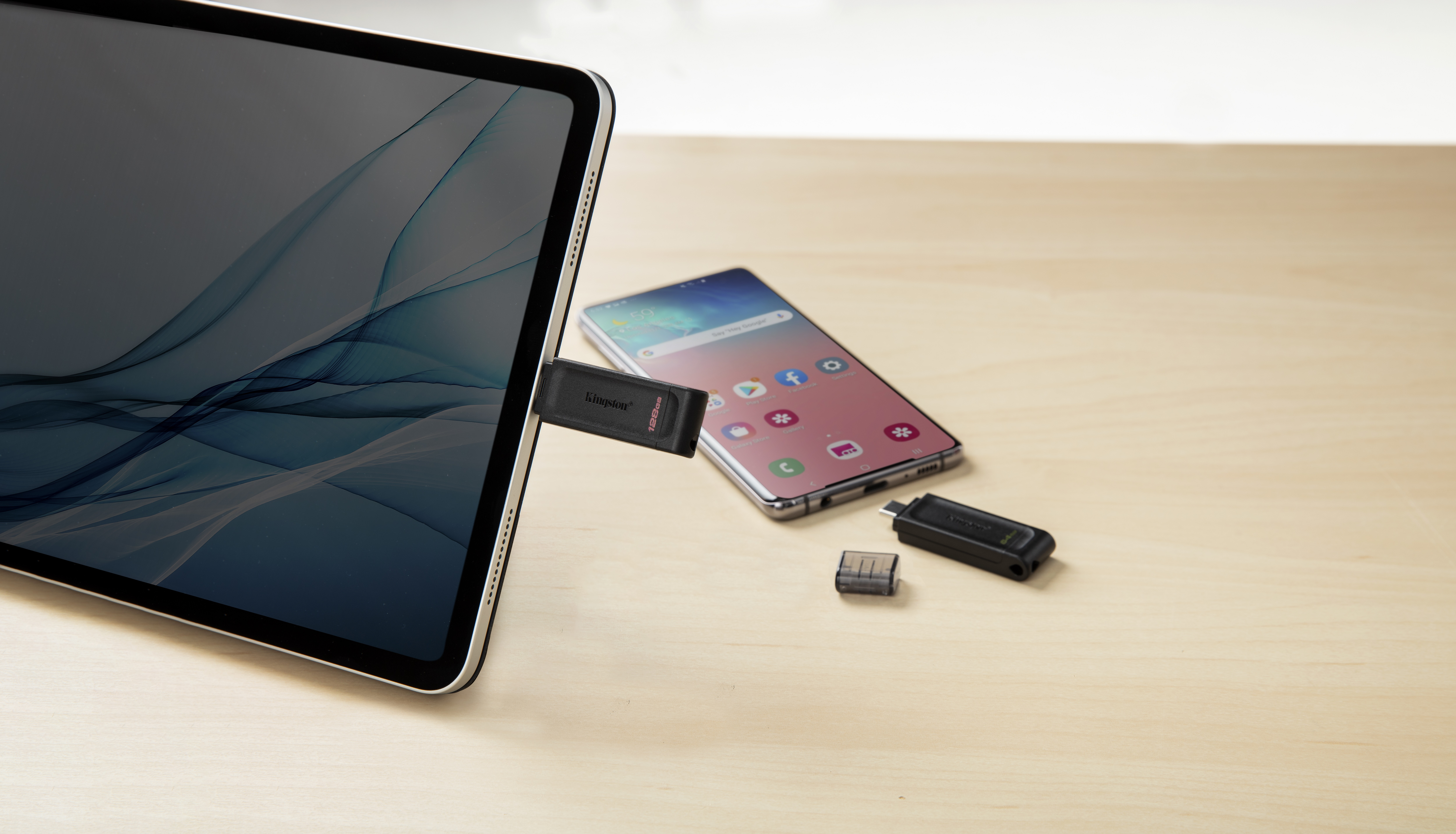 Tablet, Smartphone und USB-Stick auf Holz. Der Stick ist eingesteckt.
