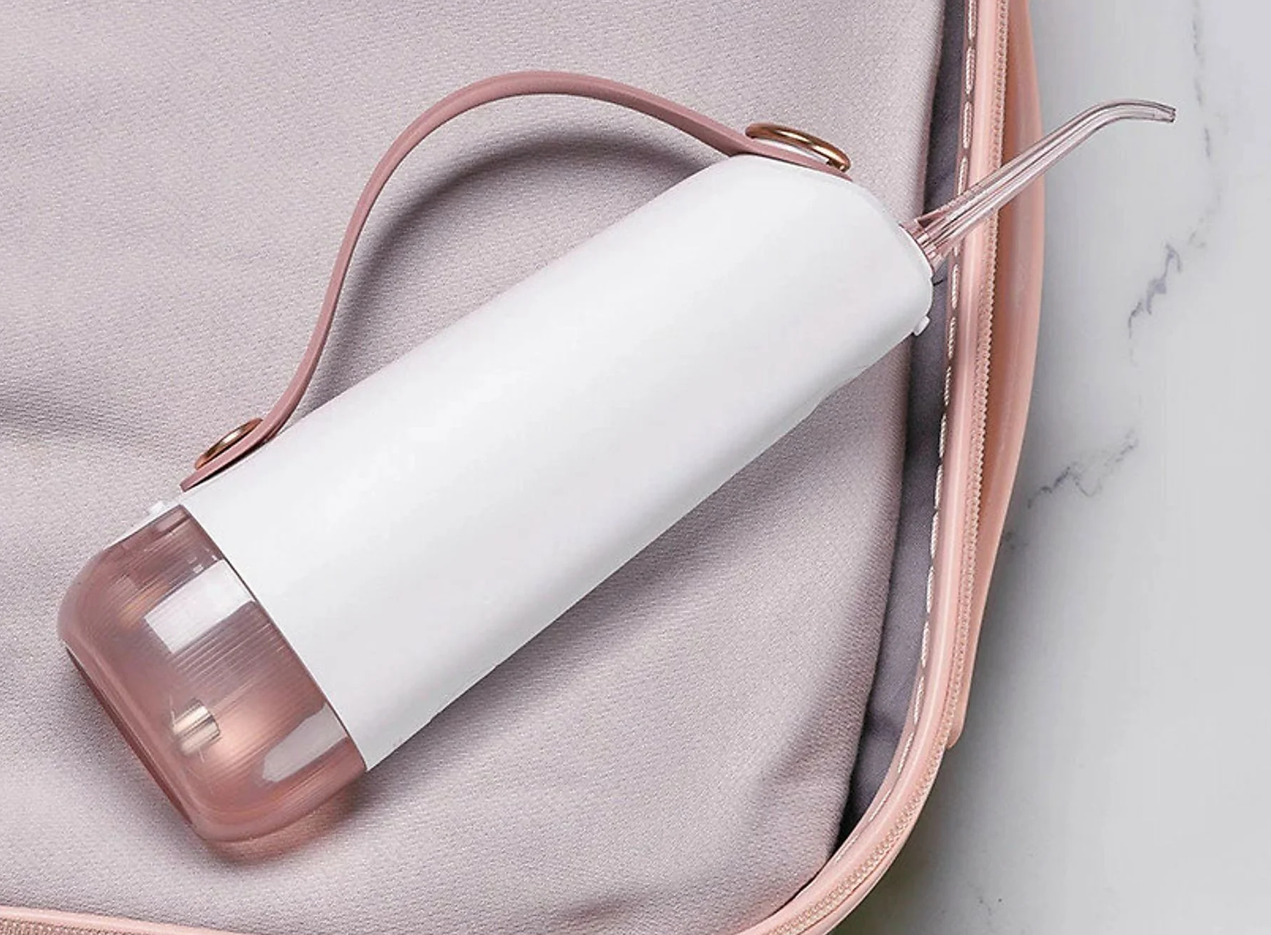 Biało-różowy irygator w szarej obudowie. Różowy uchwyt.