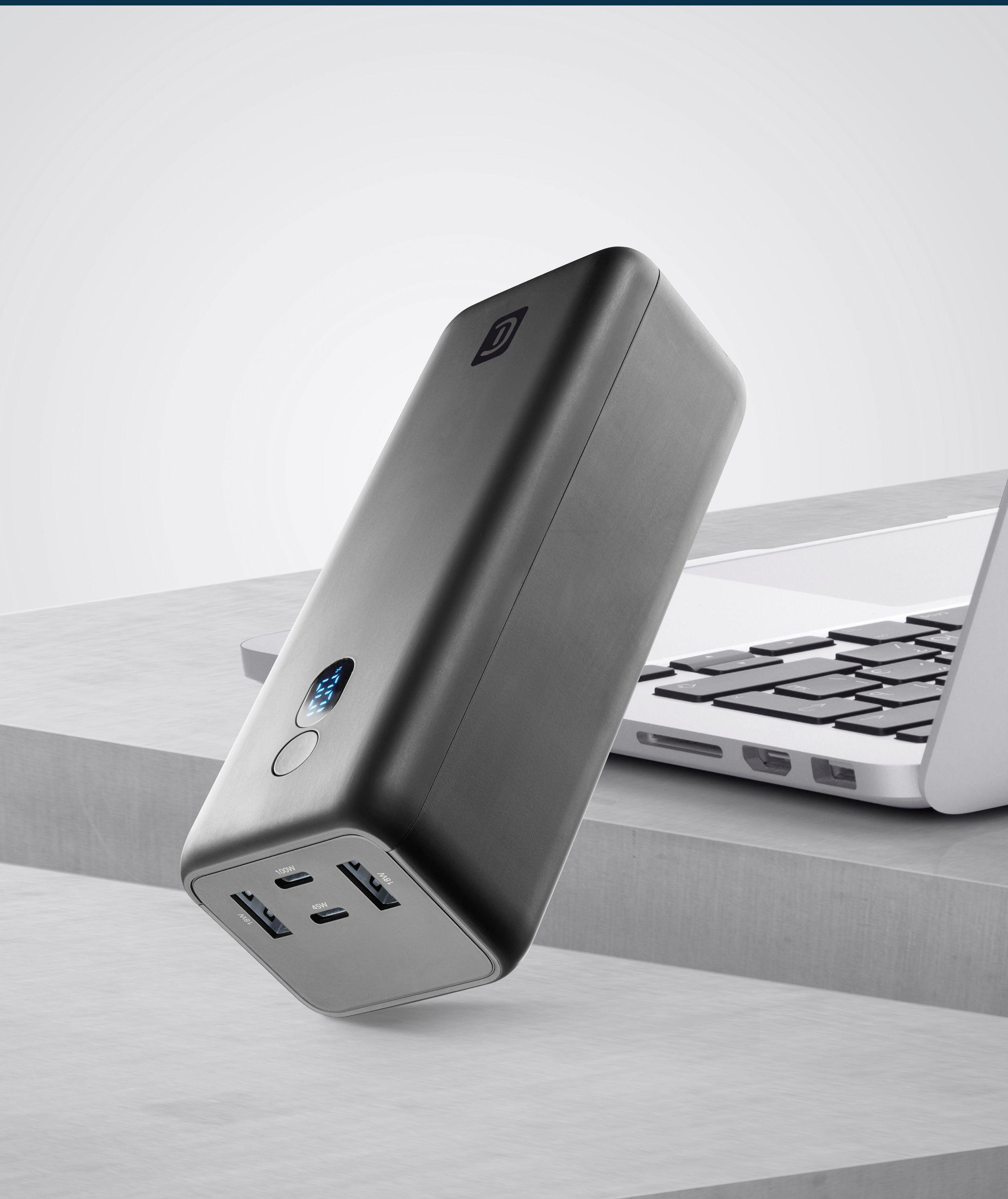 Schwarze Powerbank mit Display und USB-Anschlüssen, neben einem Laptop.