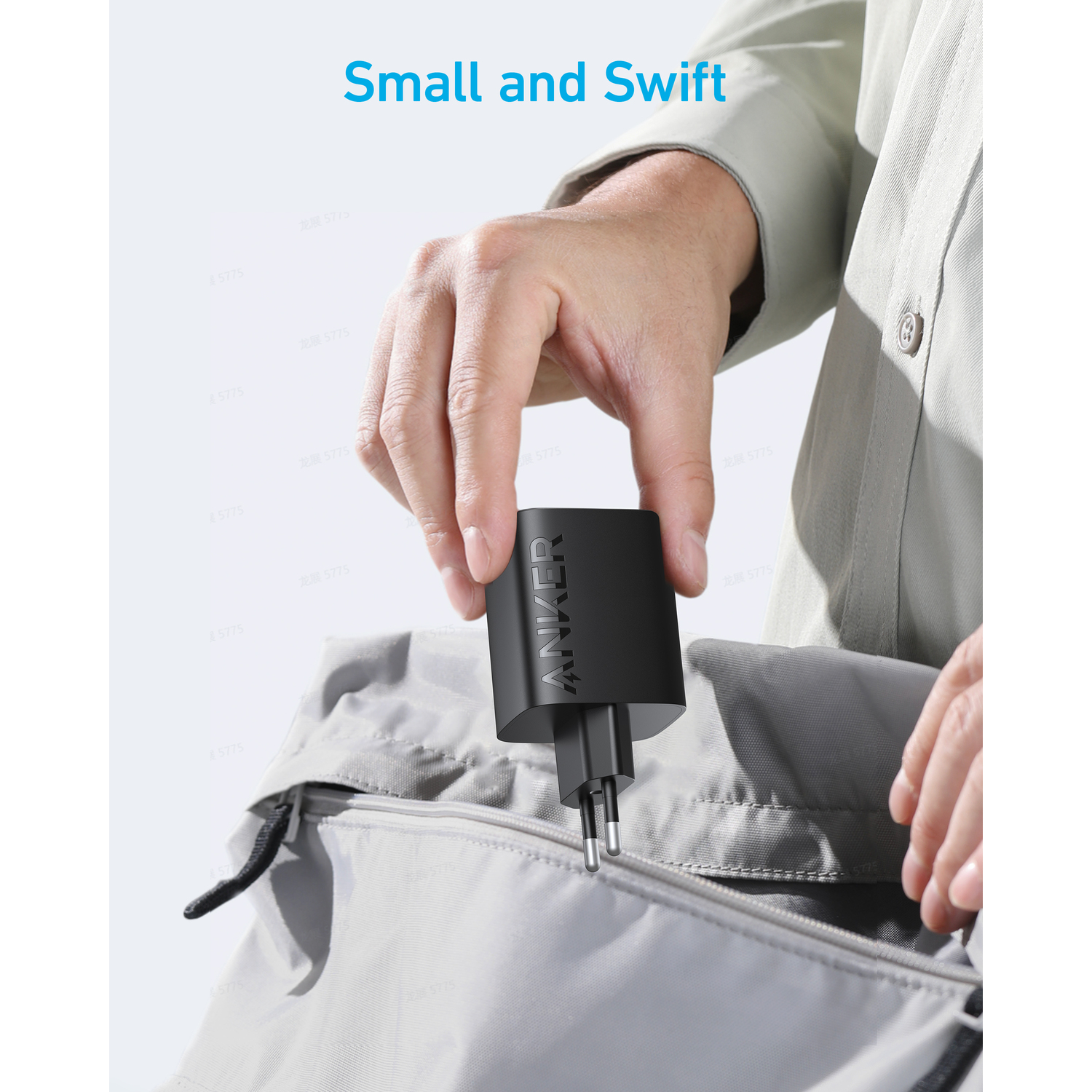 A hand holding a small black Anker charger.
