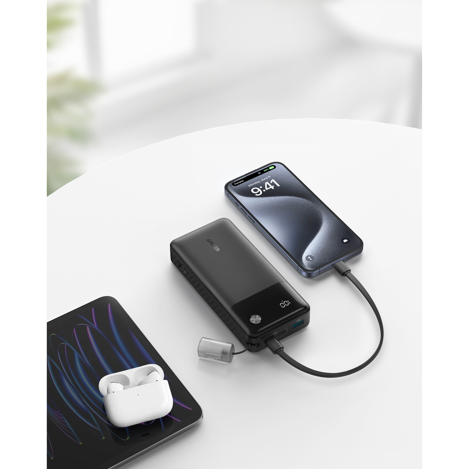 Devices charging on a white surface: phone, power bank, and earbuds case. White background.