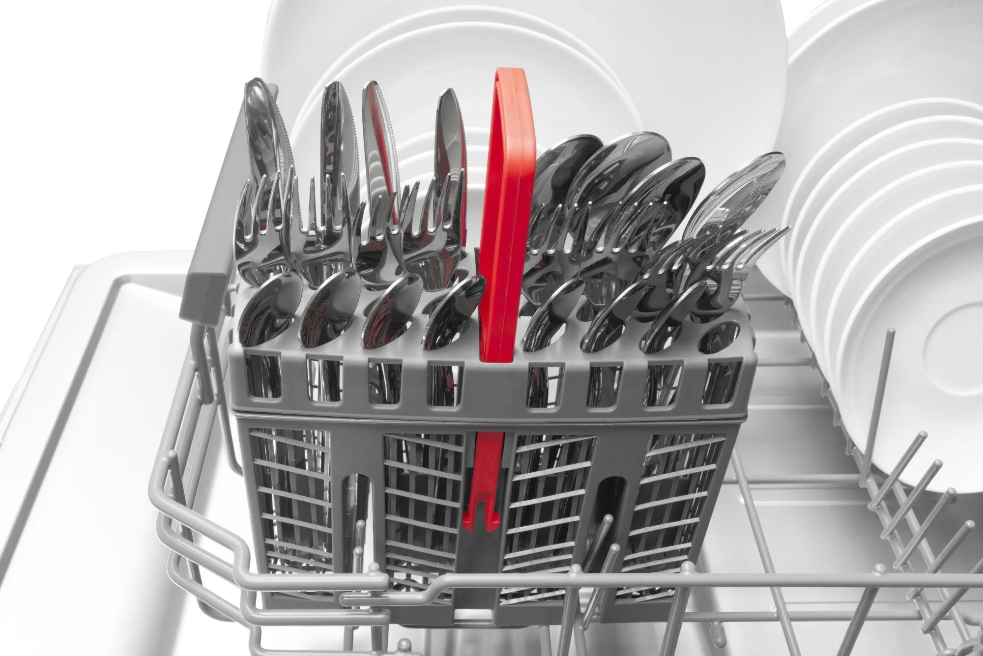 Koszyk na sztućce w zmywarce wypełniony sztućcami na białym tle.