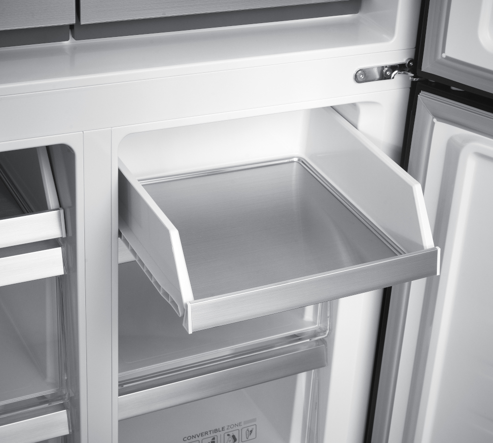 Refrigerator interior with a drawer pulled out. The drawer is stainless steel and sits on a white interior.