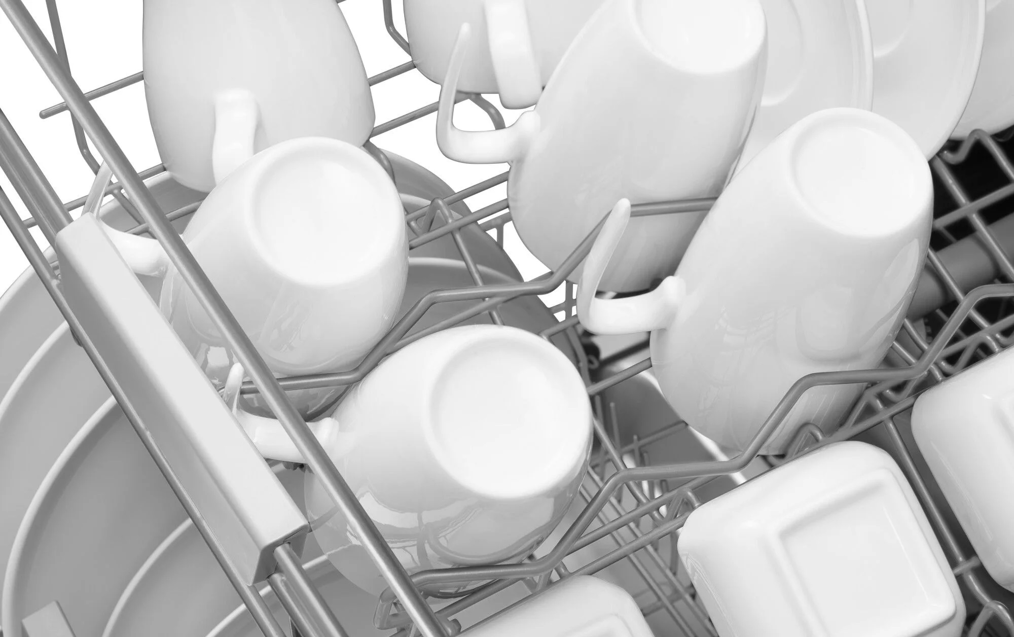 Stojak do zmywarki z białymi filiżankami i talerzami. Stojak jest metalowy.