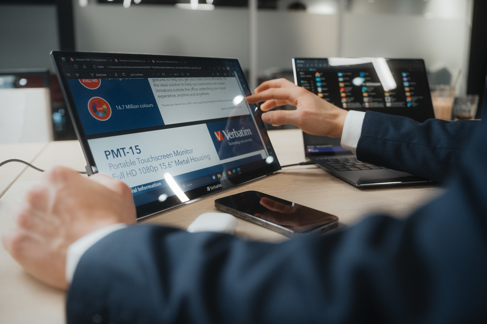Person nutzt einen Verbatim Touchscreen-Monitor, Laptop in der Nähe.
