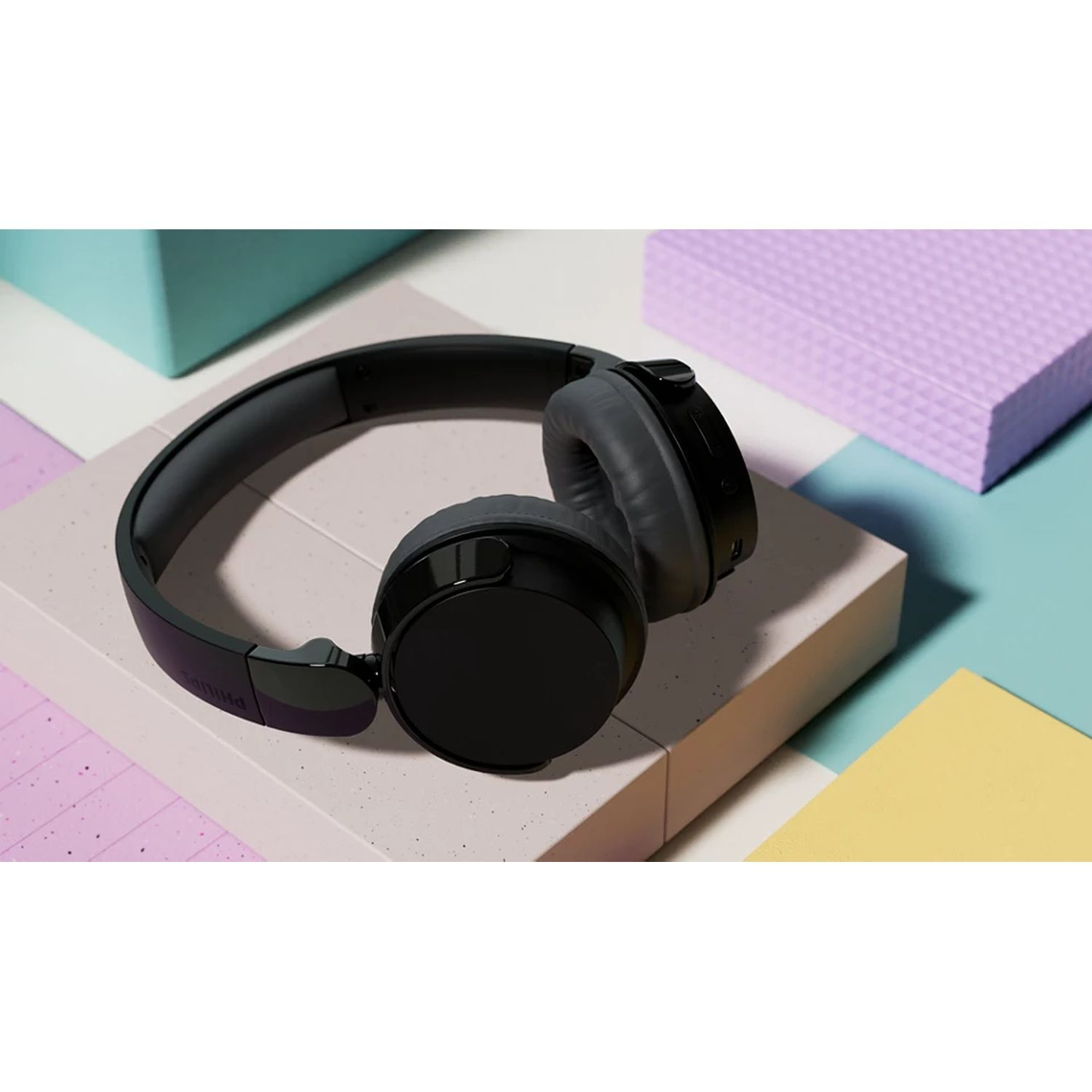 Casque audio noir sur une surface colorée avec un fond violet et jaune.