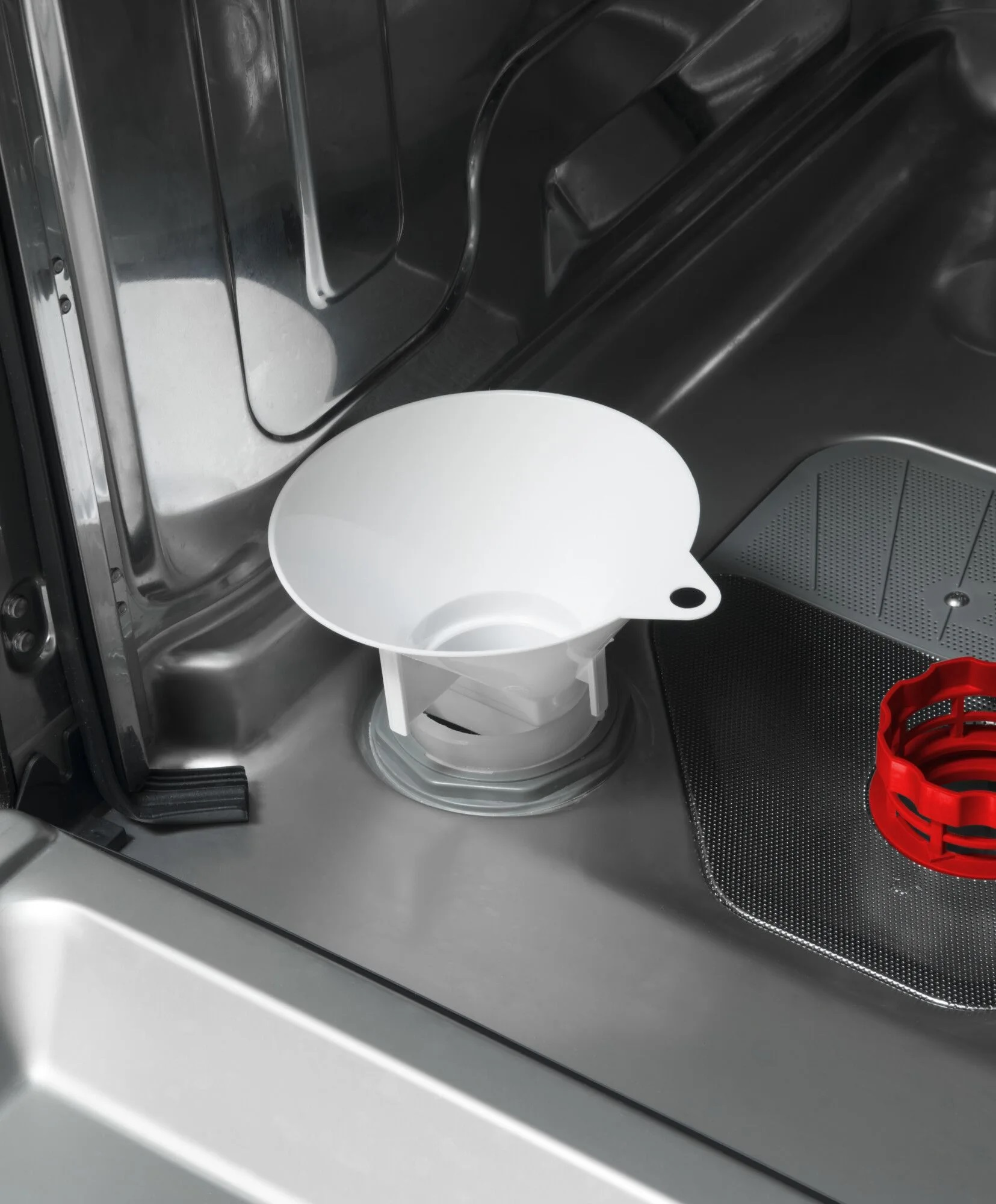 Wnętrze zmywarki z białym lejkiem pośrodku. Wnętrze jest ze stali nierdzewnej.