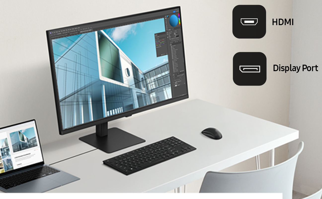 Ein Monitor, Tastatur und Maus stehen auf einem weißen Schreibtisch. Links ist ein Laptop.