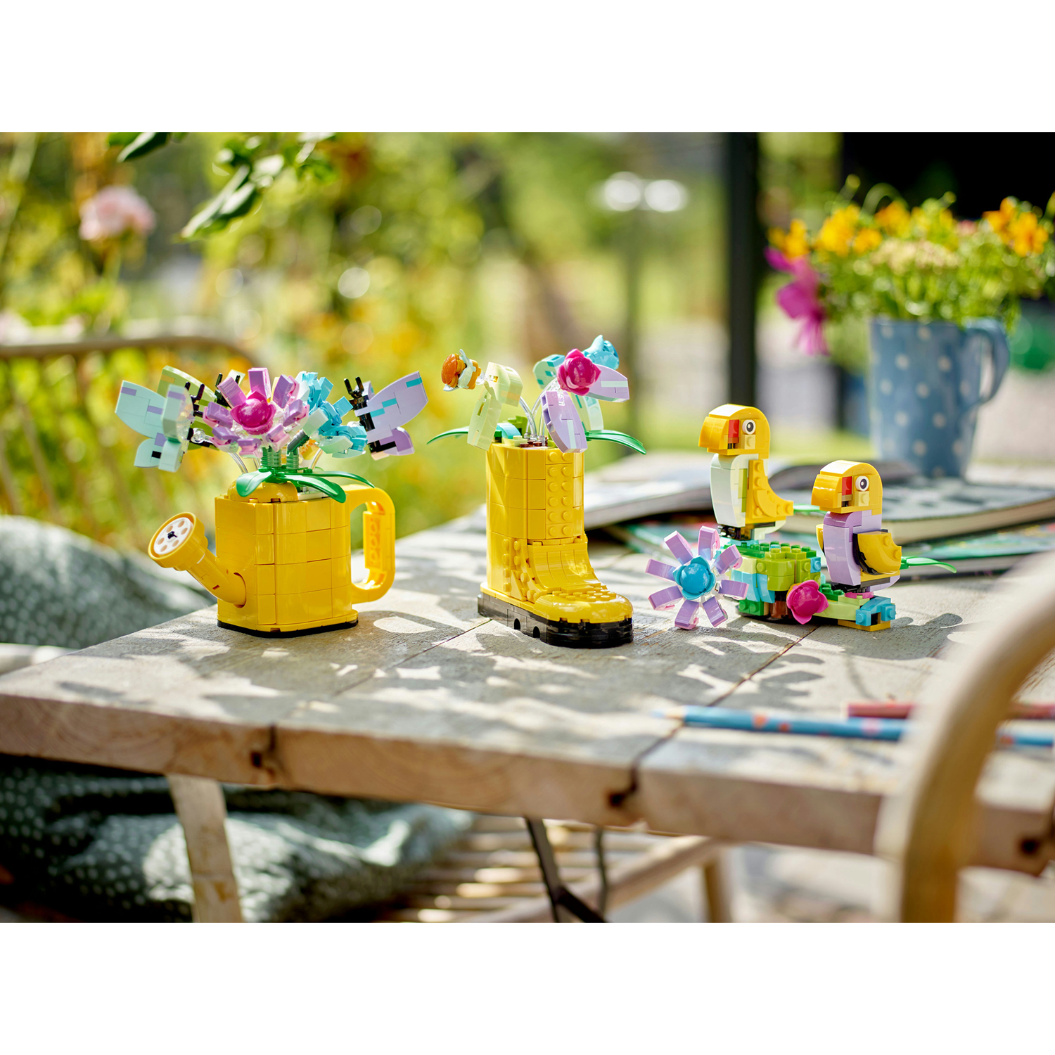 Modelli di fiori LEGO: annaffiatoio giallo, stivale e uccelli. Vari colori, su superficie in legno.
