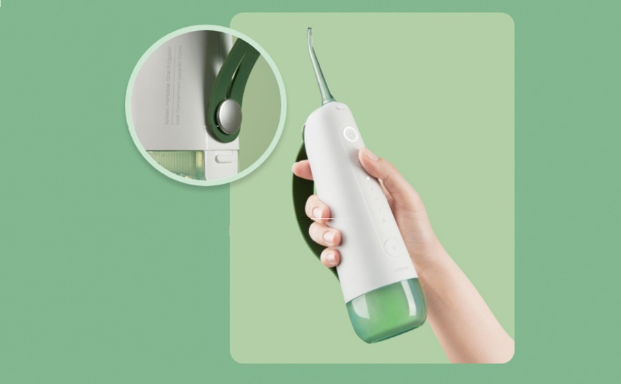 Osoba trzyma biało-zielony irygator do jamy ustnej. Irygator ma zielony zbiornik na wodę.