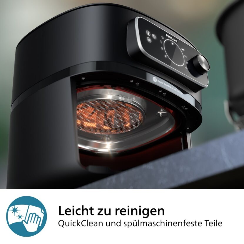 Friteuse à air noire avec la porte avant ouverte, révélant un élément chauffant.