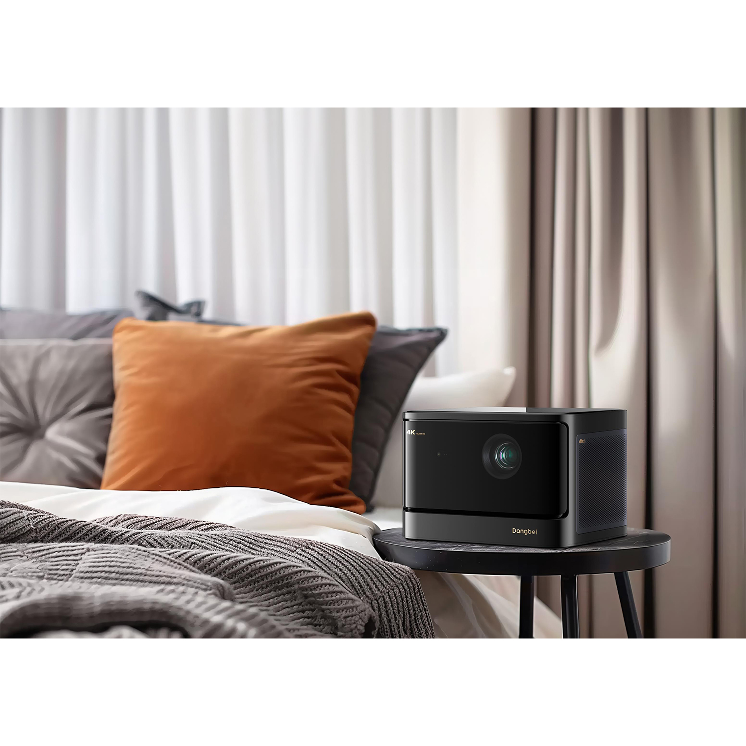 Proiettore nero su un tavolo, con un letto sullo sfondo e tende.