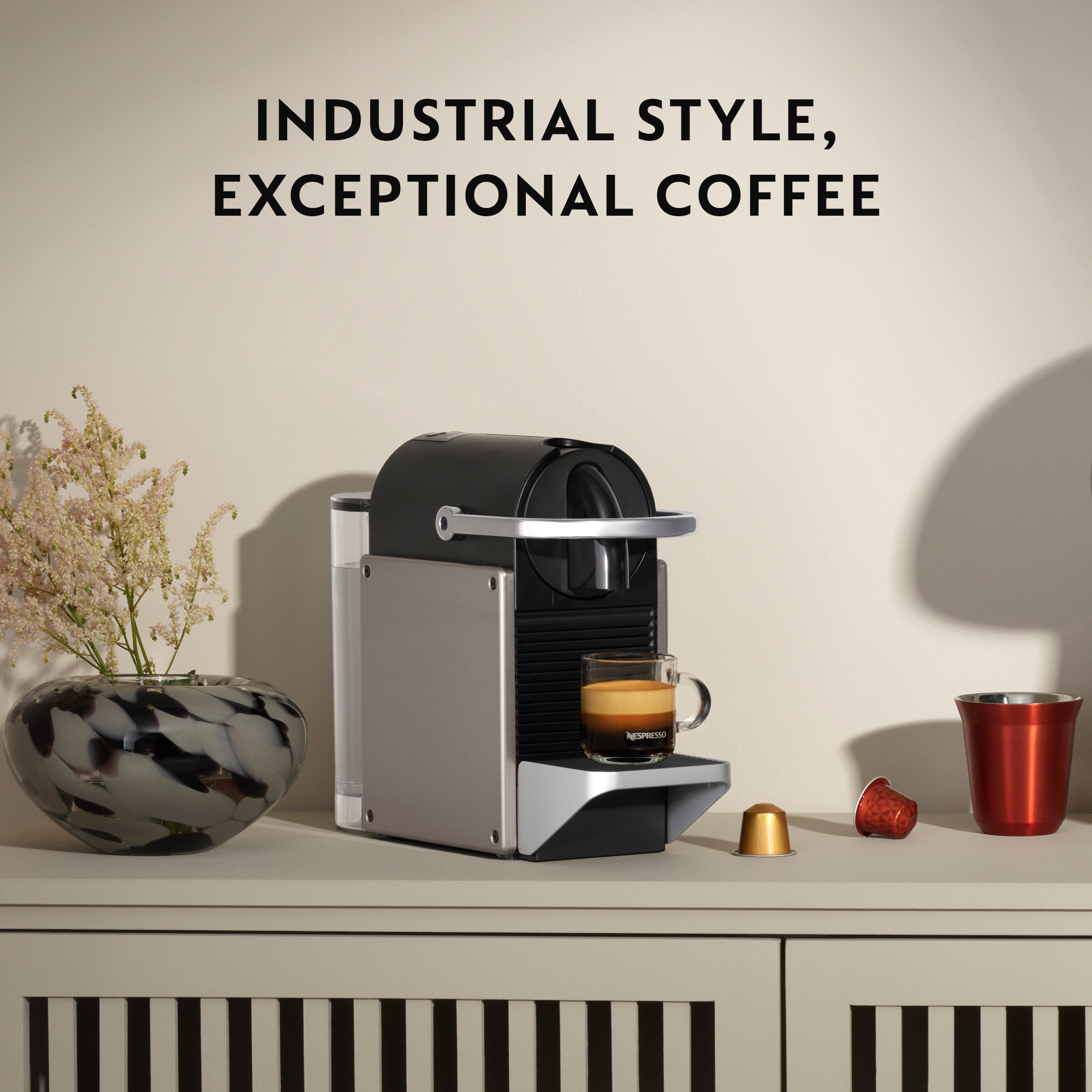 Macchina Nespresso su un mobile con una tazza di caffè. Testo in alto.