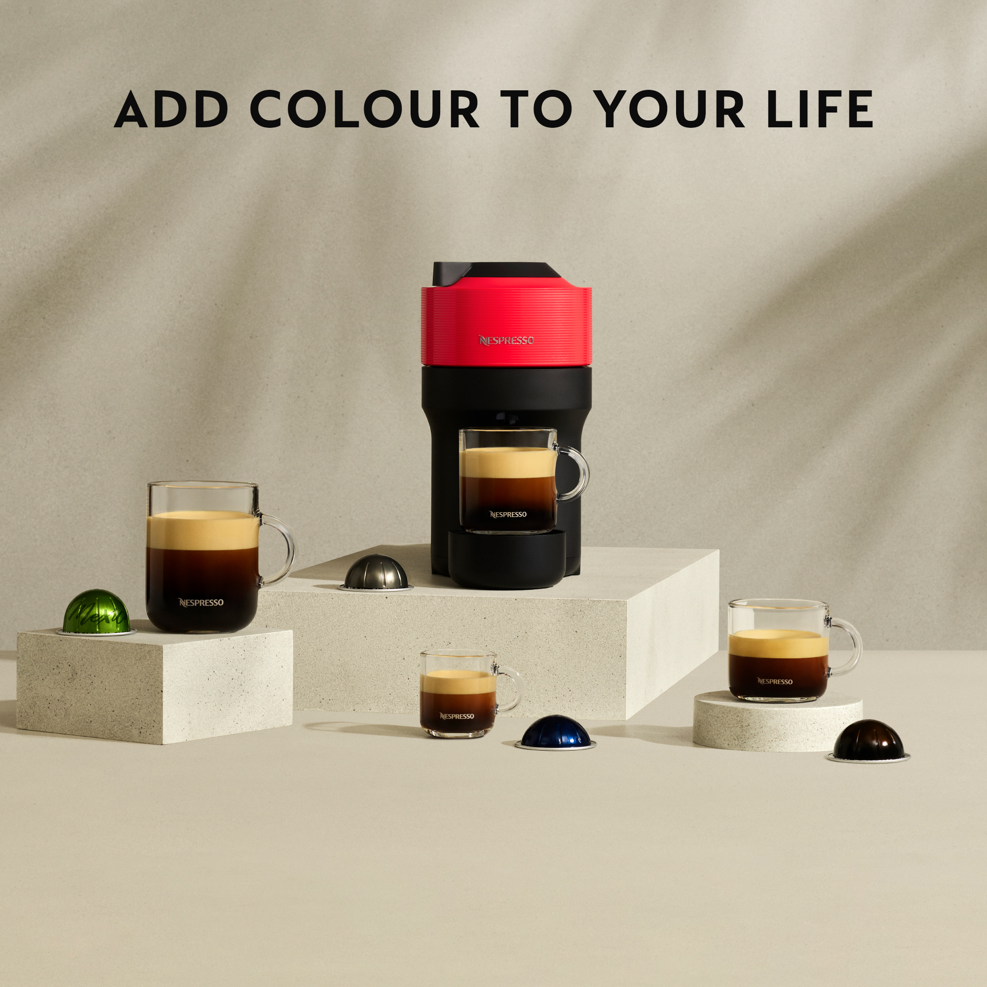Nespresso-Maschine mit Kaffeetassen und Kapseln. Die Maschine ist rot und schwarz.