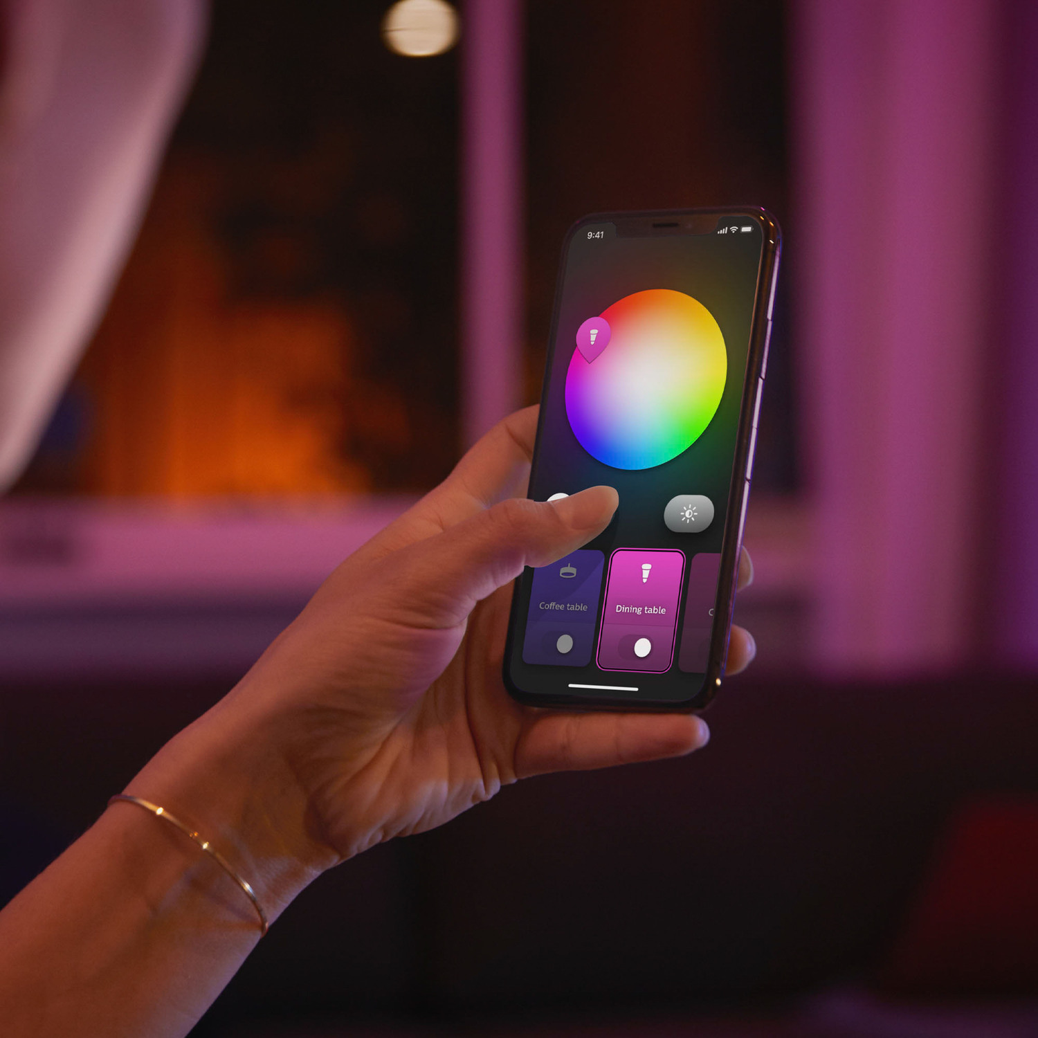 Hand holding a phone with a color wheel. Purple background.