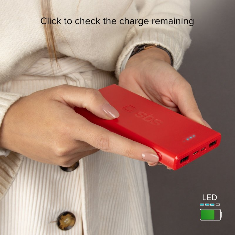 Eine rote Powerbank in Händen, mit LED-Anzeigen und einem grünen Batteriesymbol.