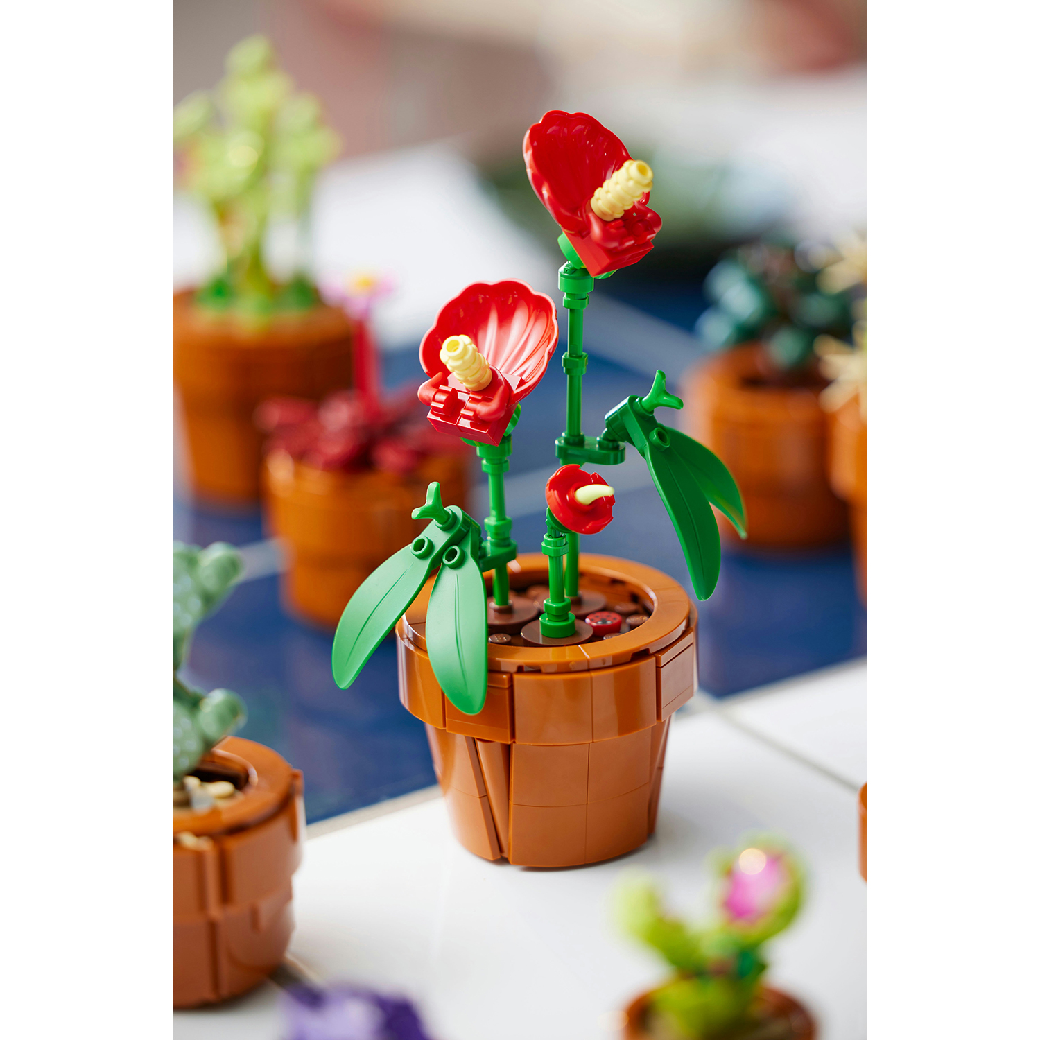 Fiori Lego in vasi marroni. Due fiori rossi sono a fuoco, con foglie e steli verdi.