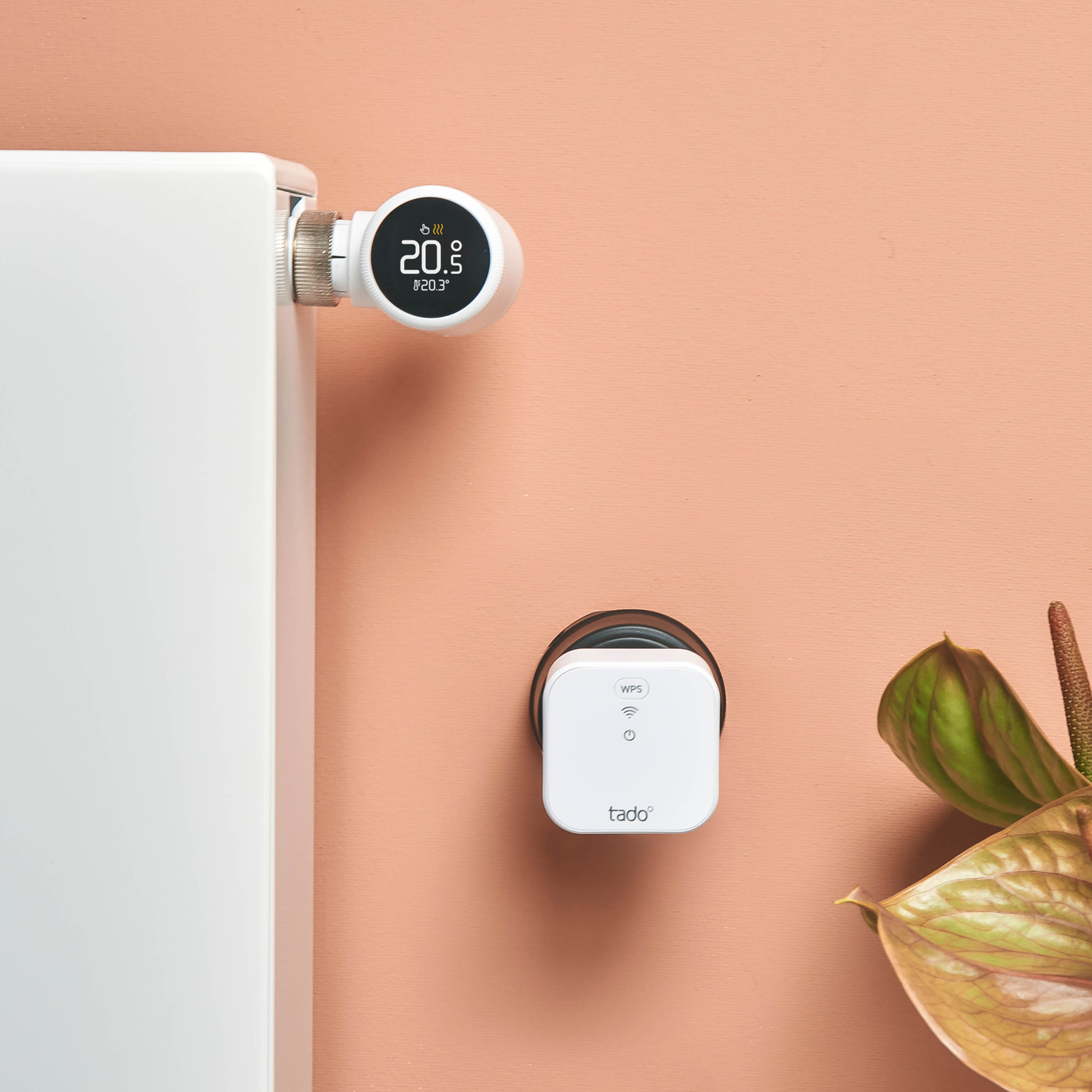 A smart thermostat and a white radiator. The thermostat displays 20.5°C. The background is a peach color.