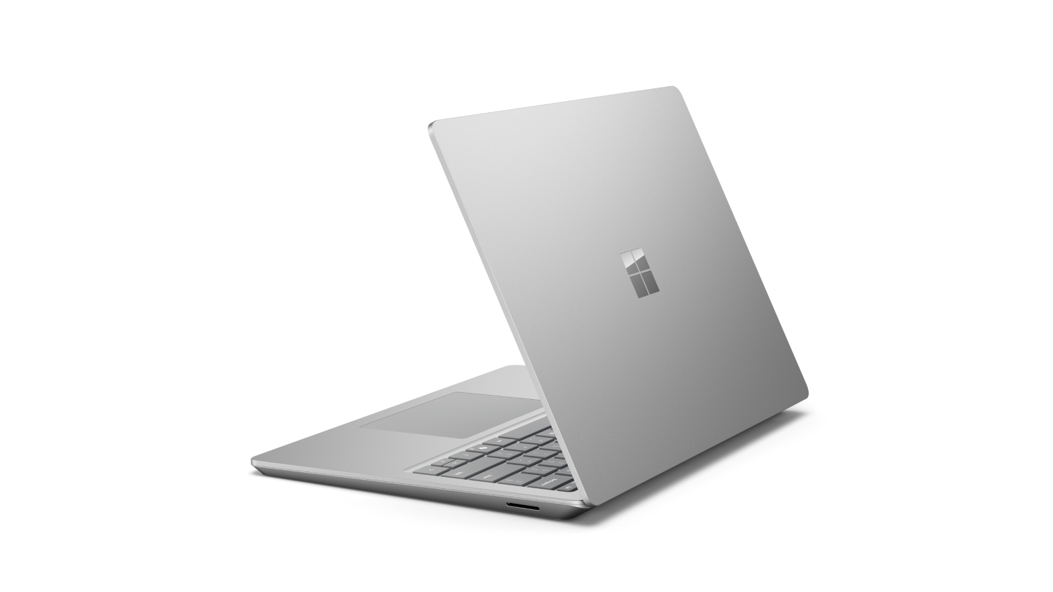 Portátil plateado, ligeramente abierto, con el logo de Microsoft.