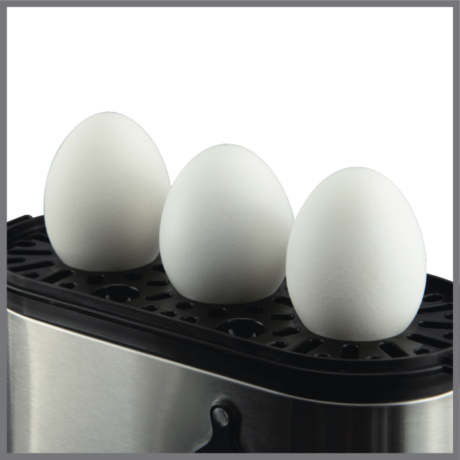 Three white eggs in an egg boiler. The boiler is silver and black.