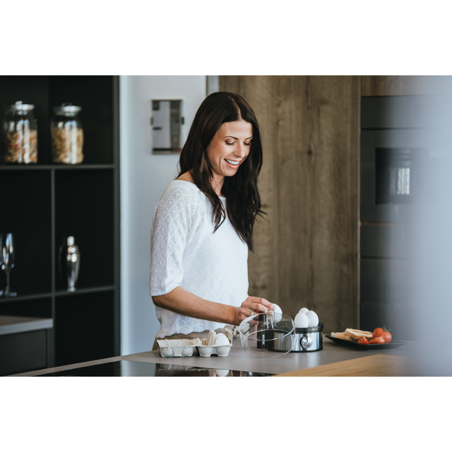 Een vrouw die eieren in een eierkoker plaatst in een keuken.
