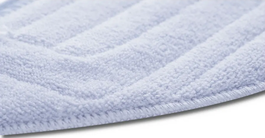 Nahaufnahme eines weißen, strukturierten Mikrofasermopppads mit geriffelten Mustern auf weißem Hintergrund.