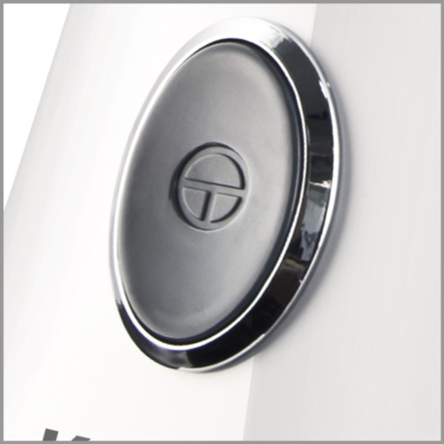 A close-up of a white appliance control button with a chrome ring and the letter 'T'.