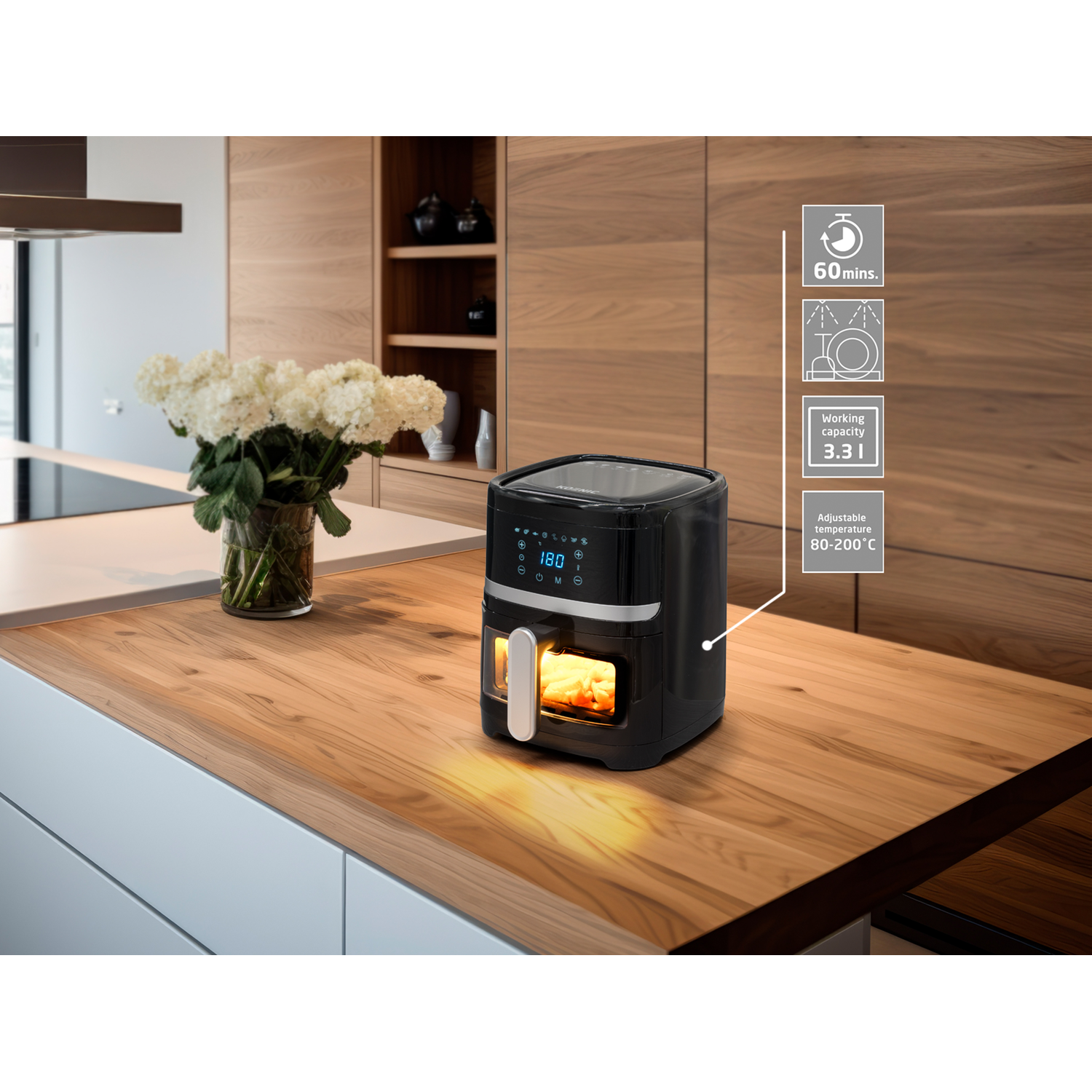 Een zwarte airfryer op een houten aanrecht, met een vaas bloemen en kooktijdaanduidingen.