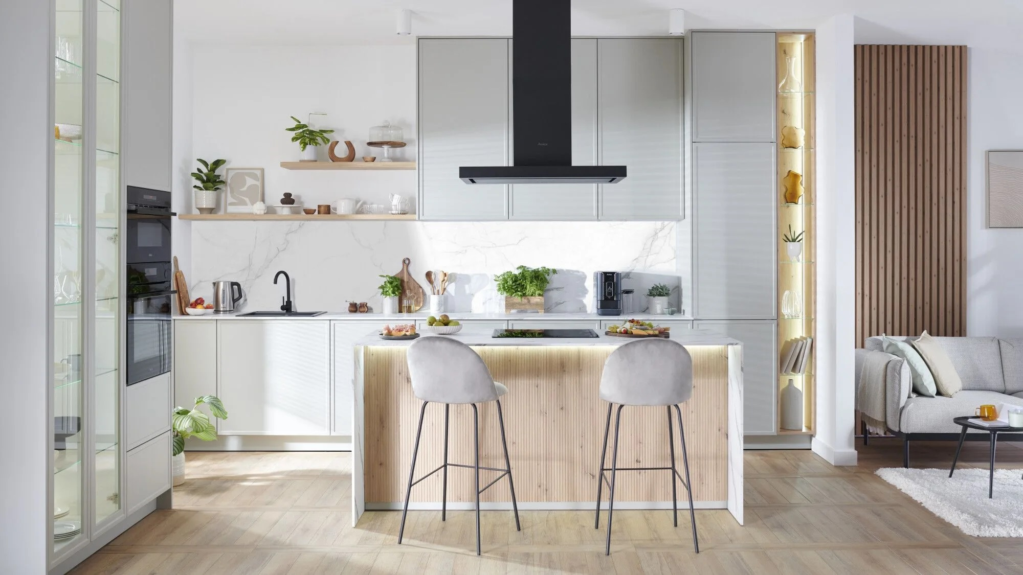 Nowoczesna kuchnia z białymi szafkami, marmurowym blatem, wyspą z hokerami i drewnianą podłogą.