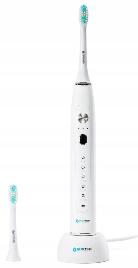 Biała elektryczna szczoteczka do zębów na stacji ładującej, z zapasową główką obok.