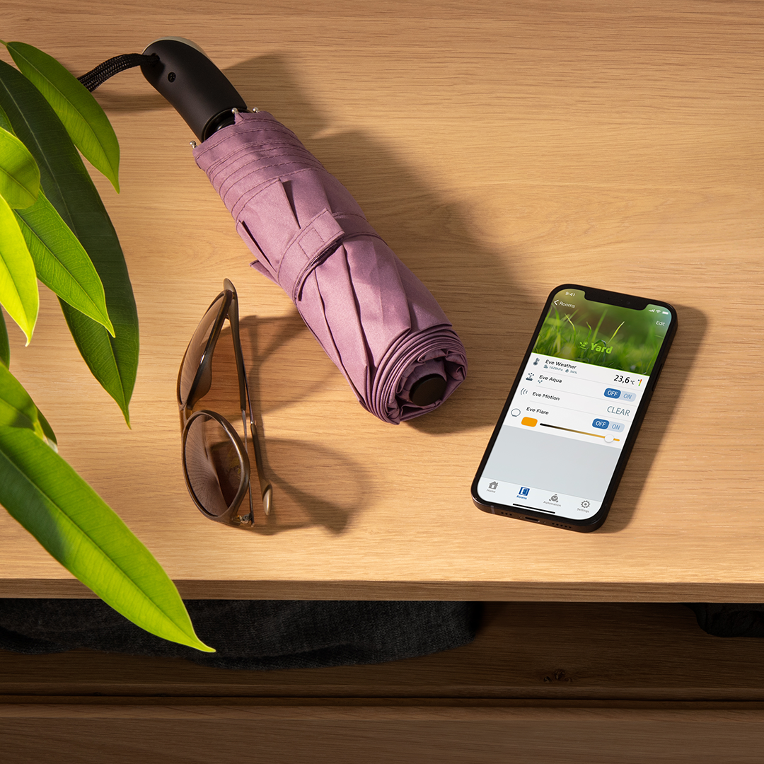 Telefon, napszemüveg és zárt esernyő fa felületen.