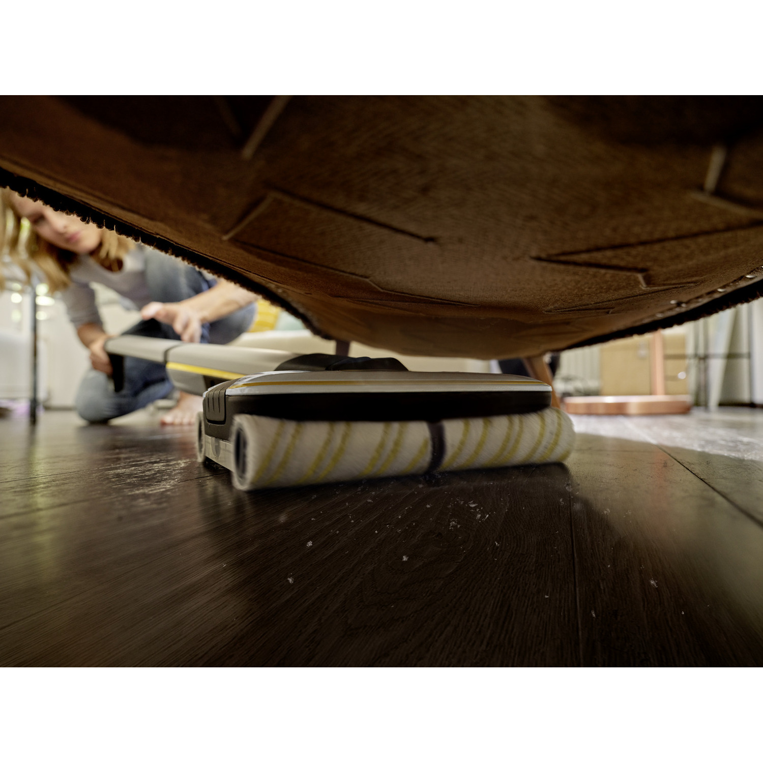 Low-angle shot of a woman cleaning a floor with a floor cleaner.