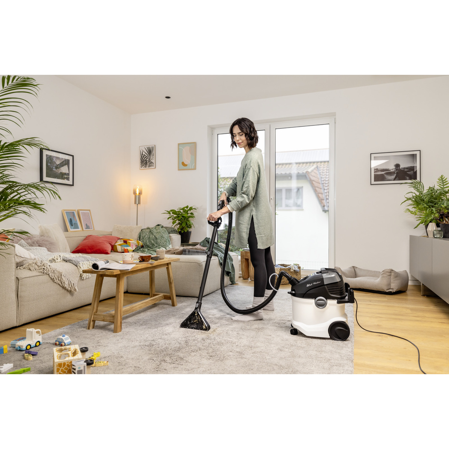 Vrouw die een tapijt stofzuigt met een schoonmaakmachine, lichte omgeving.