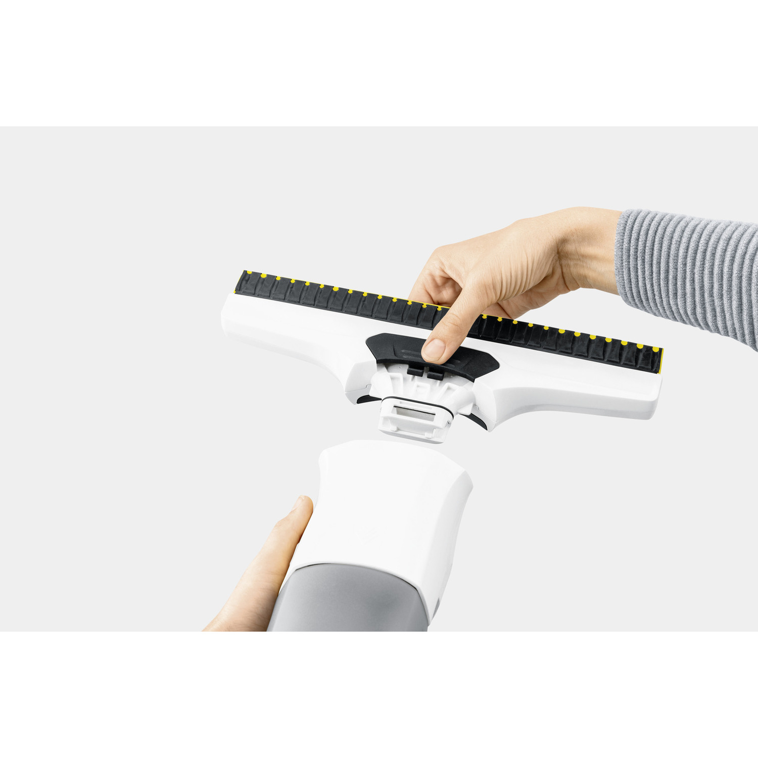 A person's hands are attaching a window cleaner head to the handle.